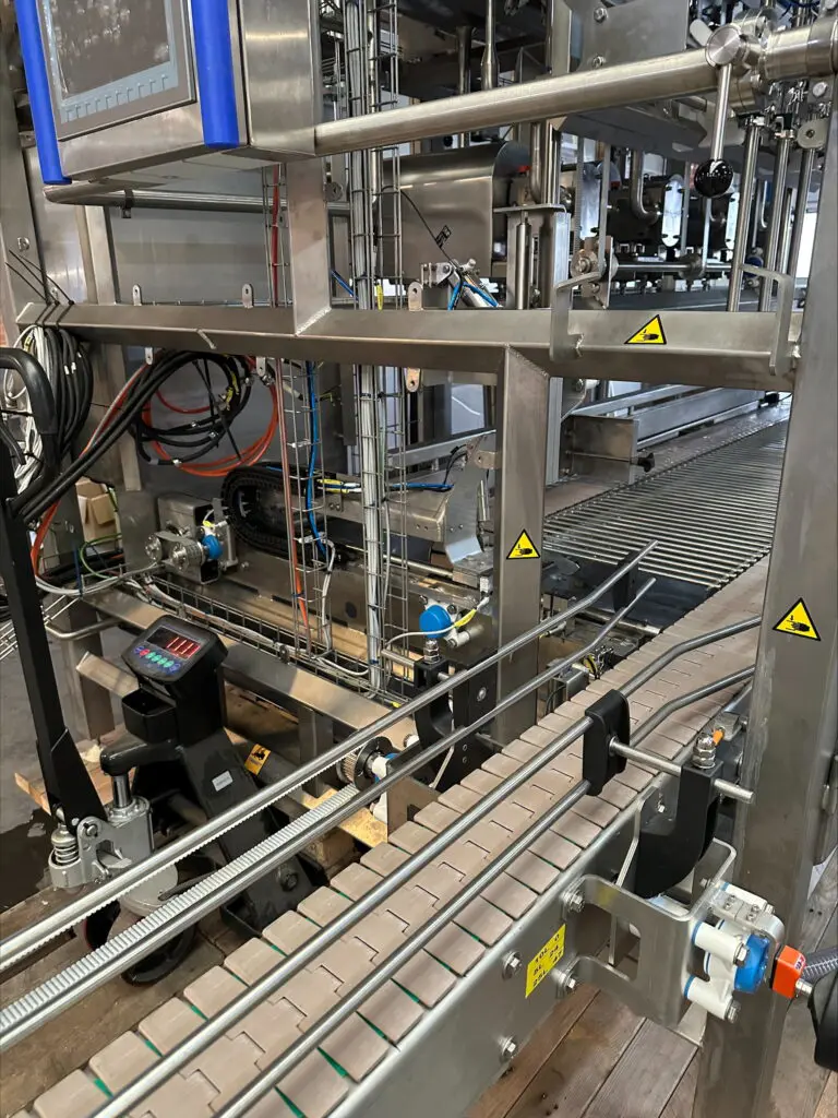 Professionelt fyldeanlæg til dunke i rustfrit stål med transportbånd og styring til fødevareproduktion.