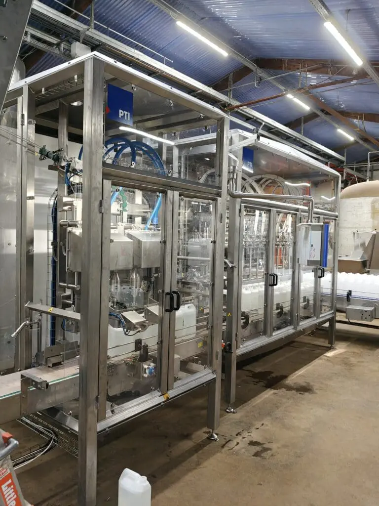 Fuldautomatisk dunkfylder i rustfrit stål til præcis påfyldning af flydende produkter i fødevareindustrien hos PTI A/S.