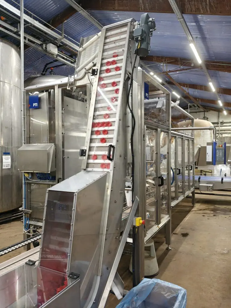 Fuldautomatisk dunkfylder med lågelevator i rustfrit stål til hygiejnisk fødevareproduktion.